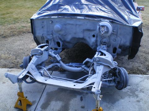 1964 Ford Galaxie - The front end of a car, with the engine bay covered and the chassis supported by jack stands, is shown in a state of disassembly.