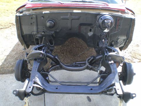 1964 Ford Galaxie - The front suspension and chassis of a red 1964 Ford Galaxie are visible, with the engine bay area exposed.