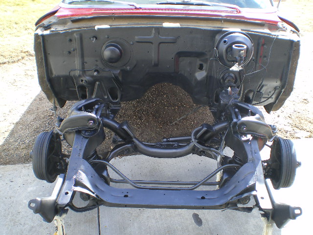 Red car chassis with black painted front suspension and wheels, viewed from the front