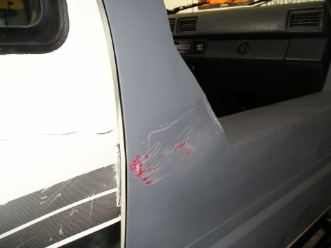 1986 Toyota Hilux - Scratched gray side panel and interior of a truck, with visible dashboard and door details.