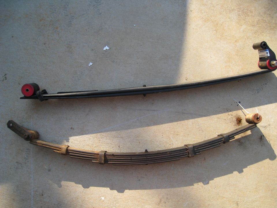 Two leaf springs, one new with red bushings, one old and rusty
