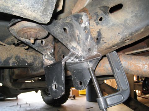 1996 Ford Bronco - Custom suspension bracket modification on a vehicle frame, with a C-clamp holding it in place.