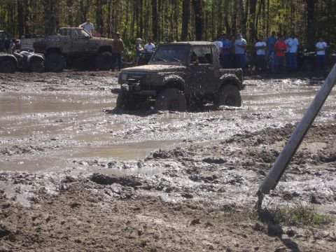 1989 Ford Bronco - Multiple vehicles participate in a mud bogging event with spectators watching.