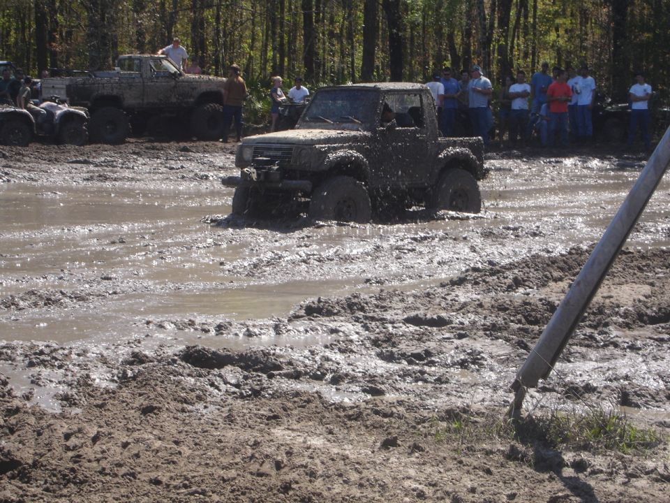 Muddy off-road truck stuck in mud pit, front view