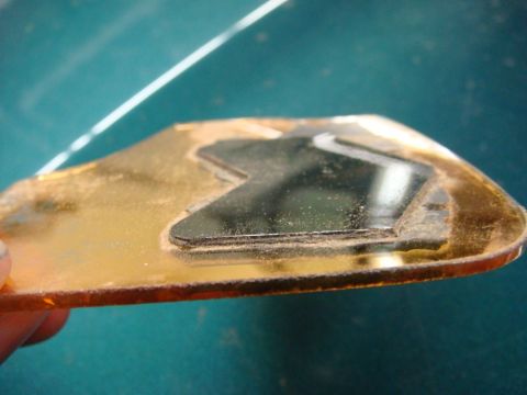 1996 Ford Bronco - A close-up view of a gold-colored signal mirror part with a black inset, showing dust accumulation.