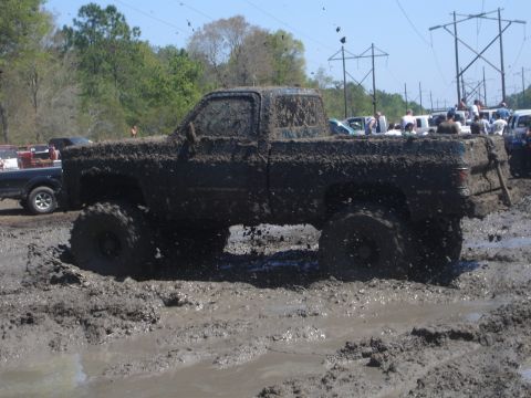 1989 Ford Bronco - Pickup truck covered in mud during an off-road event.