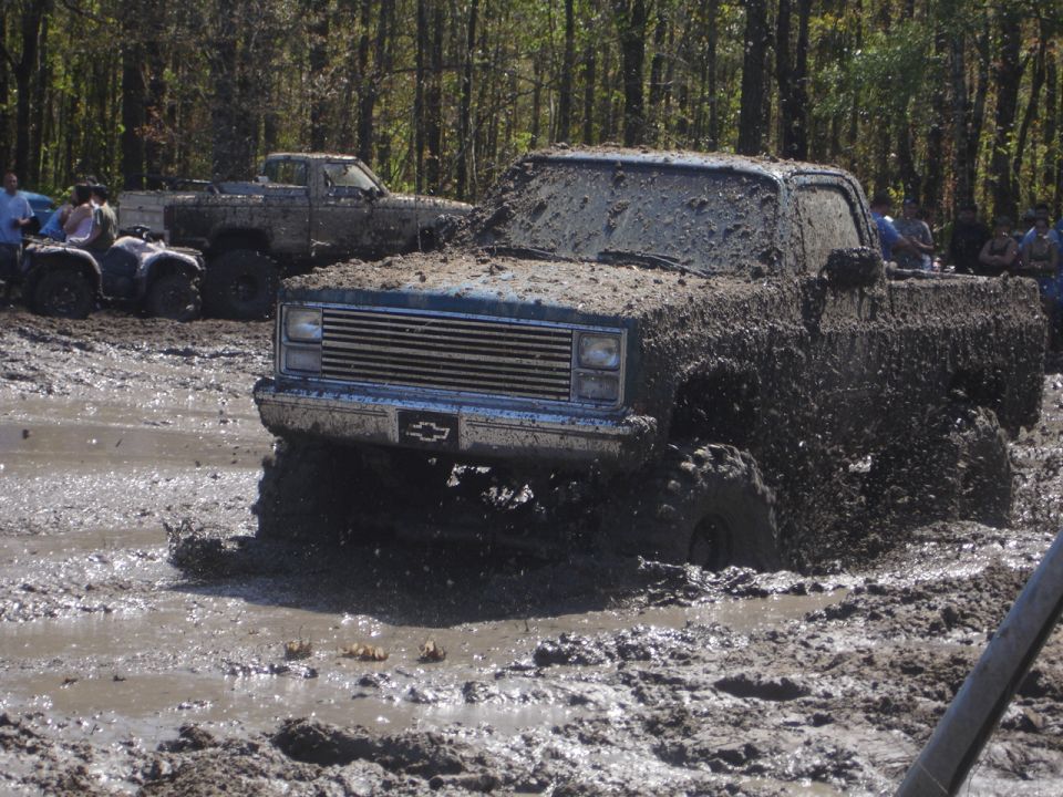 Mud-covered pickup truck stuck in mud, front view