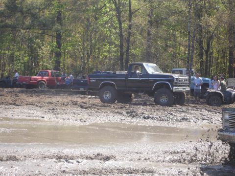 1989 Ford Bronco - Several trucks and ATVs are stuck in the mud at an off-road park.