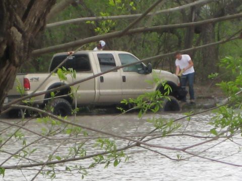 1996 Ford Bronco - A tan Ford F-250 Super Duty is stuck in water with two people nearby.