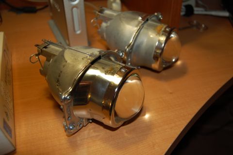1985 Mercury Grand Marquis - Two projector headlights are shown on a desk, likely for a custom vehicle modification project.