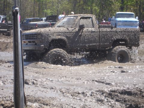 1989 Ford Bronco - This pickup truck is covered in mud as it navigates through a challenging off-road course.