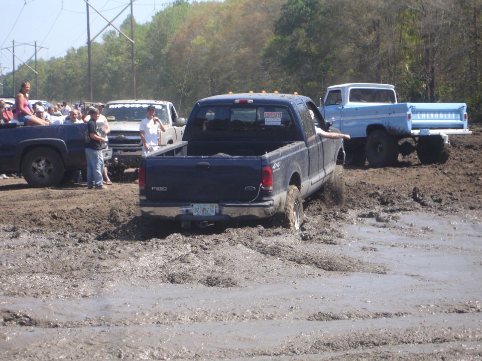 Dark blue Ford F-250 stuck in mud, rear view. License plate B23-9276