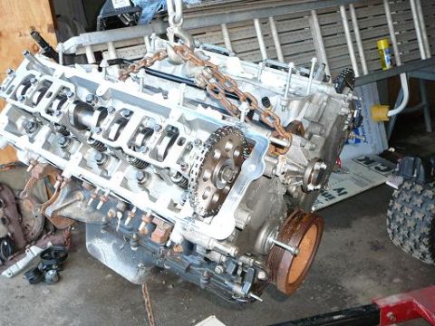 1997 Mercury Grand Marquis - Engine block is hoisted by chains, showing internal components and timing chain mechanism.