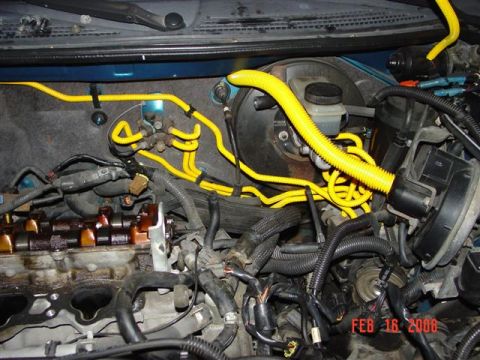 1993 Ford Probe - Close-up view of an engine bay, prominent yellow wiring and the brake booster assembly.