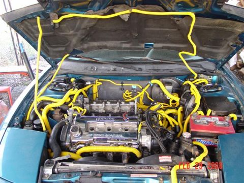 1993 Ford Probe - Engine bay of a teal car, a V6 engine and extensive yellow hose modifications.