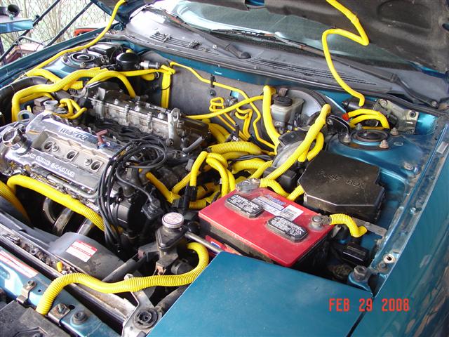 Engine bay with yellow hoses and a red battery. Text reads FEB 29 2008 SUPERMOTORS