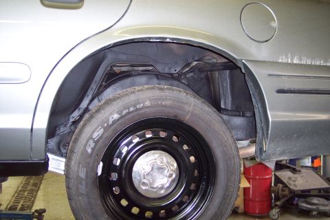 2001 Ford Crown Victoria - The rear wheel well of a 2001 Ford Crown Victoria is shown, revealing its silver exterior.