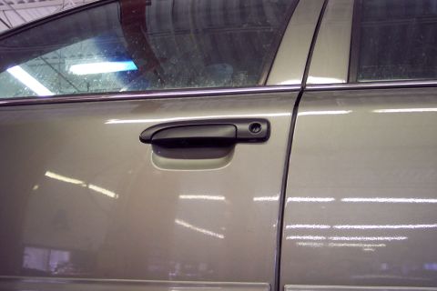 2001 Ford Crown Victoria - The side of a car is shown, focusing on the door handle and window trim. The vehicle appears to be in an indoor setting.