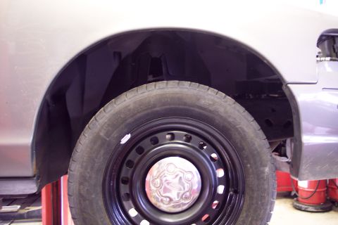 2001 Ford Crown Victoria - The image shows a close-up view of a car's wheel well and tire, focusing on the black steel wheel.