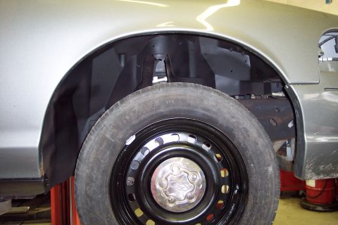 2001 Ford Crown Victoria - The front wheel and wheel well of a 2001 Ford Crown Victoria are visible, with the vehicle raised on a lift.