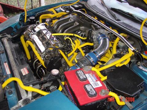 1993 Ford Probe - The engine bay is filled with bright yellow hoses and custom chrome parts.