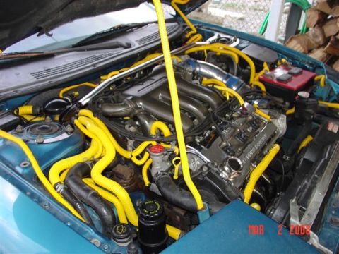 1993 Ford Probe - The engine bay of a 1993 Ford Probe shows extensive yellow hose modifications and a teal exterior paint.