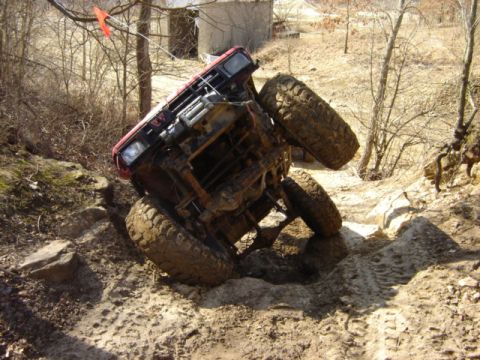 1992 Ford Bronco - This red off-road vehicle appears to be stuck while navigating a challenging rocky and muddy terrain, with visible "SUPERMOTORS.NET" brandi…