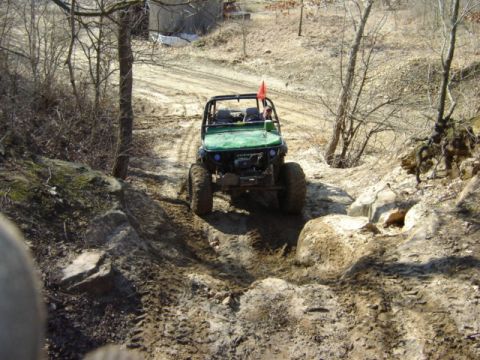 1992 Ford Bronco - An off-road vehicle tackles a challenging muddy and rocky path, demonstrating its capabilities on rough terrain.
