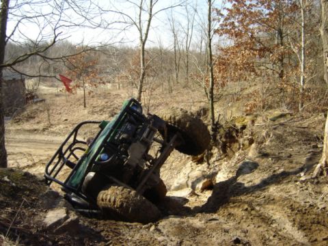 1992 Ford Bronco - An ATV is stuck in a muddy ditch with trees and dirt banks surrounding it.