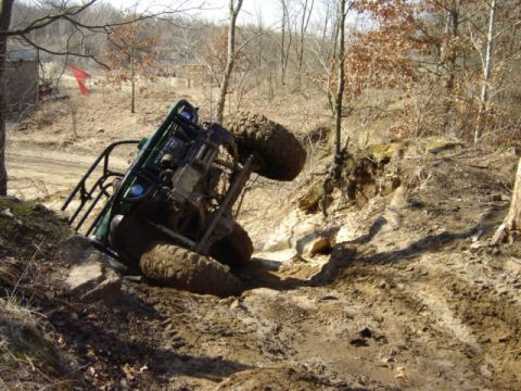 1992 Ford Bronco - An off-road vehicle is stuck on its side on a challenging dirt trail.