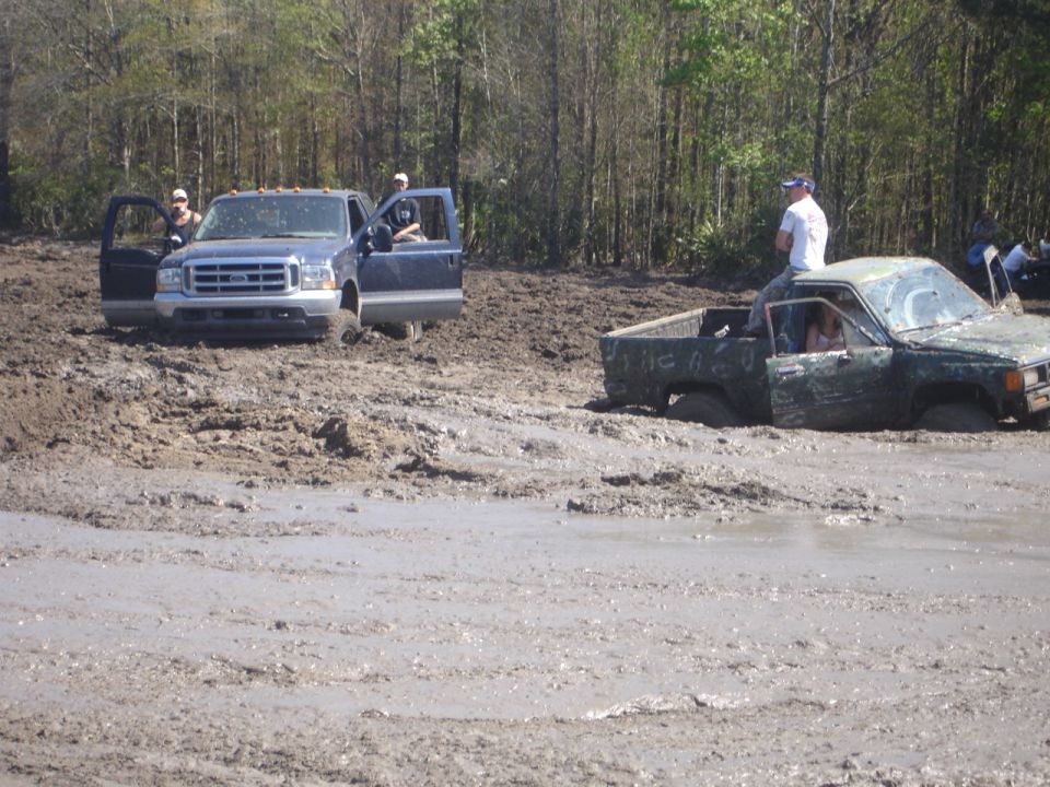 Two trucks stuck in mud, one dark blue, one green