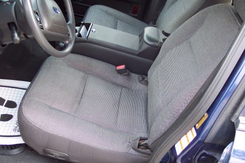 2001 Ford Crown Victoria - The interior of a Ford Crown Victoria, fabric seats and a center console with cup holders.