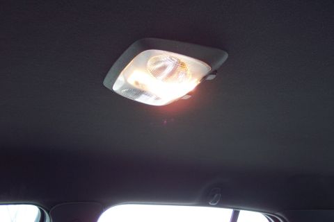 2001 Ford Crown Victoria - The interior dome light of a vehicle is illuminated against the dark headliner.