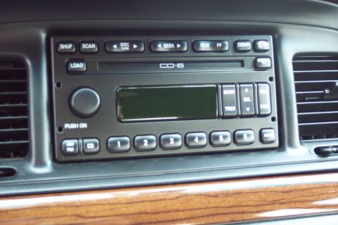 2001 Ford Crown Victoria - Close-up of a car's interior dashboard, focusing on the CD player and wood grain trim.