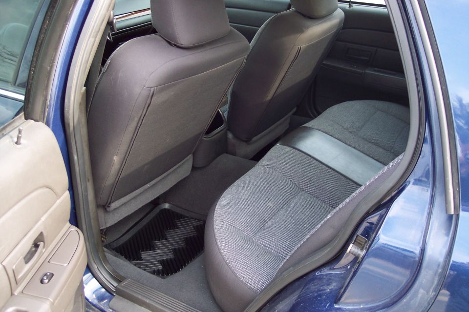Rear seats and floor of a blue sedan, showing fabric upholstery and a black floor mat