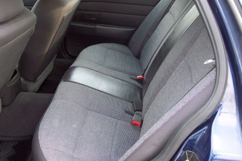 2001 Ford Crown Victoria - The interior of a vehicle is shown, focusing on the back seat and its grey fabric upholstery.