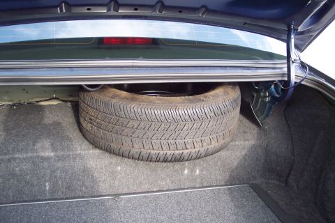 2001 Ford Crown Victoria - Spare tire stored in the trunk of a dark blue vehicle.