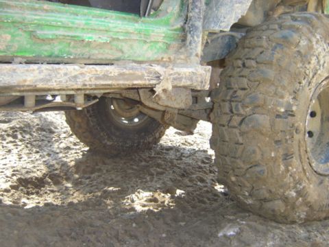 1992 Ford Bronco - This off-road vehicle, covered in mud, shows its side profile with prominent, heavily treaded tires.