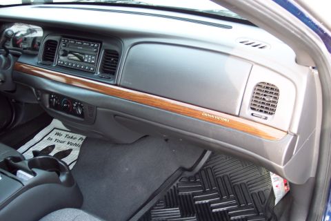 2001 Ford Crown Victoria - The interior of a Crown Victoria features wood grain trim and a floor mat with text.