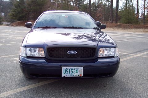 2001 Ford Crown Victoria - A dark blue 2001 Ford Crown Victoria is parked in a lot, showing its front grille and license plate.