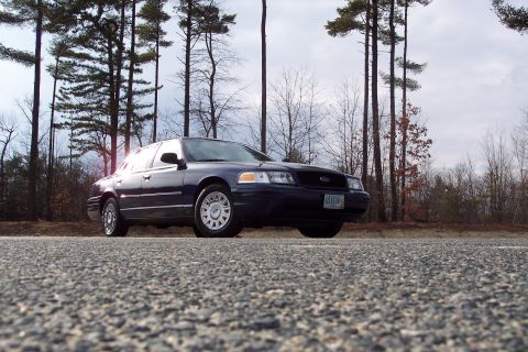2001 Ford Crown Victoria - Dark blue 2001 Ford Crown Victoria seen from a low angle on a cloudy day.