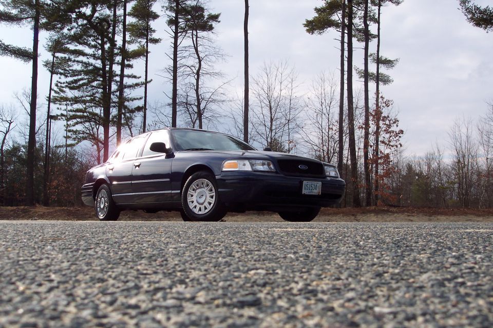 2001 Ford Crown Victoria parked on the side of a road with trees in the background