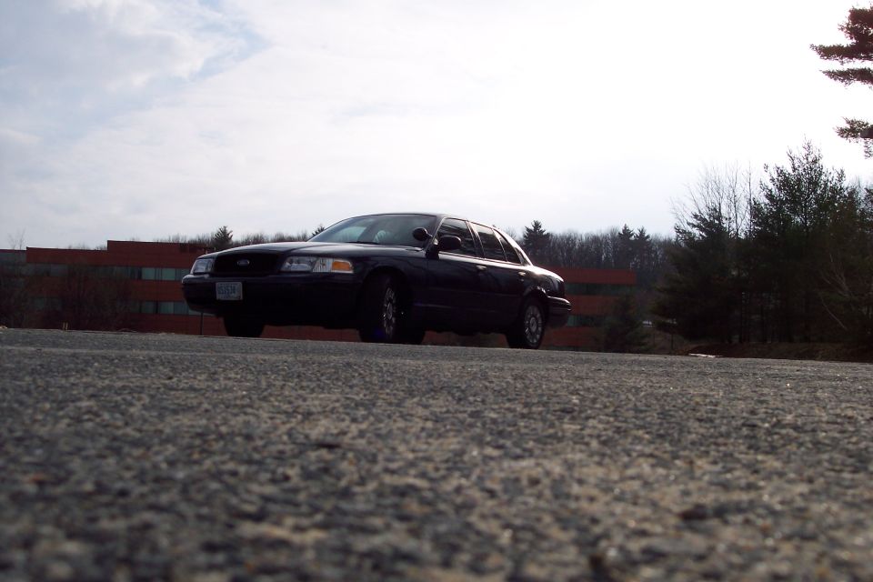 Black 2001 Ford Crown Victoria parked on asphalt, low angle view