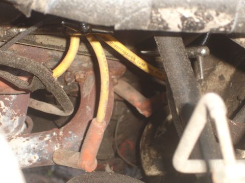 1989 Ford Bronco - Close-up view of engine components, including yellow spark plug wires and a rusted exhaust manifold.