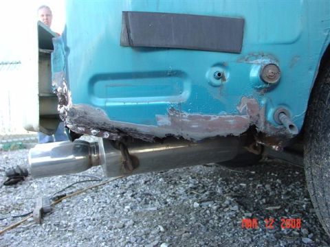1993 Ford Probe - A person stands behind the damaged rear quarter panel of a teal vehicle, revealing extensive rust.