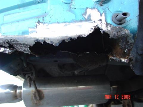 1993 Ford Probe - Severe rust damage is visible on the car's undercarriage, with an exhaust pipe in view.