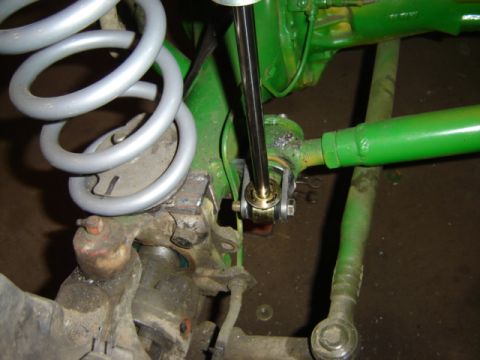 1992 Ford Bronco - Detail shot of suspension parts, including a shock absorber and coil spring, with a green painted axle and visible 'SUPERMOTORS.NET' waterm…