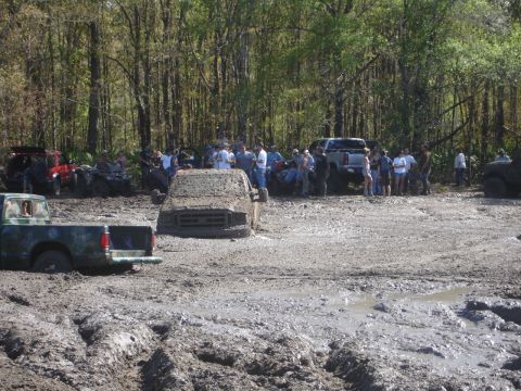1989 Ford Bronco - Multiple vehicles are stuck in the mud during an off-road event.
