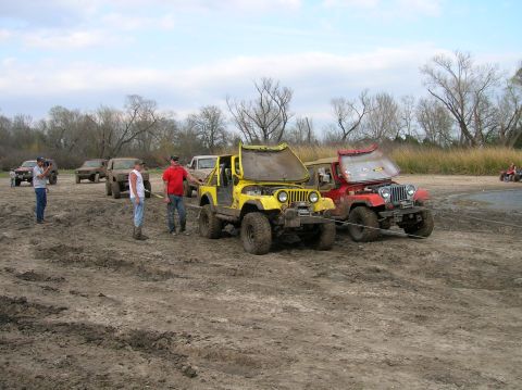 1996 Ford Bronco - Two off-road vehicles, a yellow Jeep and a red Jeep, are stuck in the mud with their hoods open.