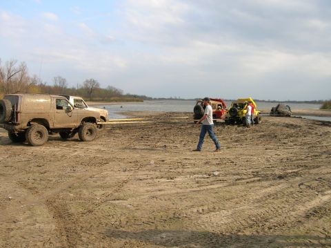 1996 Ford Bronco - Several off-road vehicles are being towed across a muddy beach area.